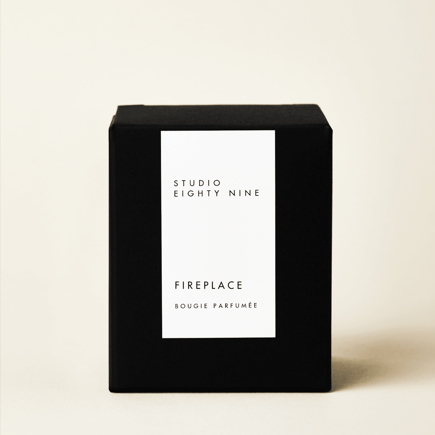 Classic-sized black cubic candle box with a white minimalist rectangular vertical label on the front, featuring the brand "STUDIO EIGHTY NINE", scent "FIREPLAC", and product "BOUGIE PARFUMÉE" in clean, uppercase typography.