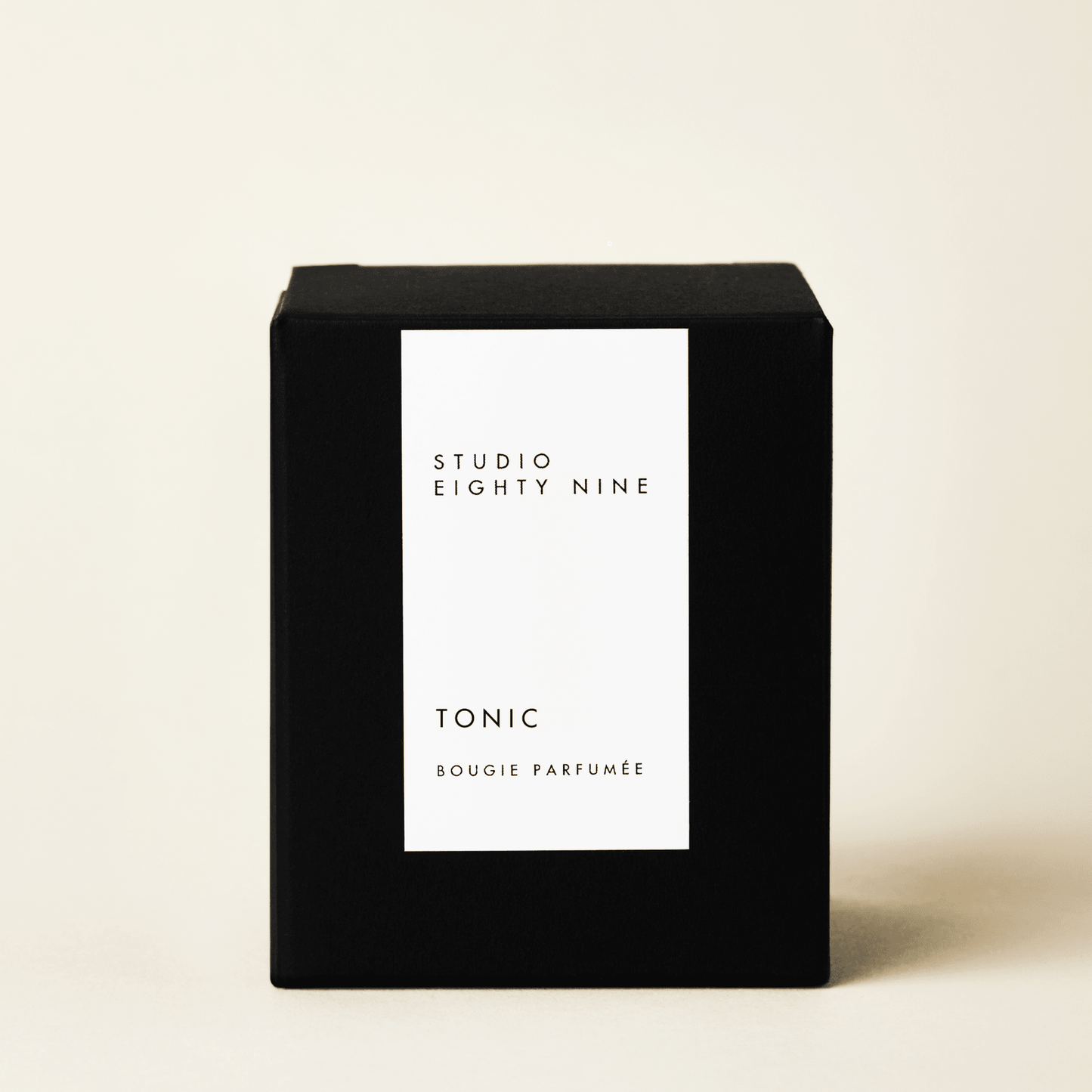 Classic-sized black cubic candle box with a white minimalist rectangular vertical label on the front, featuring the brand "STUDIO EIGHTY NINE", scent "TONIC", and product "BOUGIE PARFUMÉE" in clean, uppercase typography.